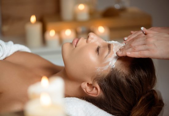 Young beautiful brunette girl in mask for face relaxing in spa salon. Eyes closed. Copy space.